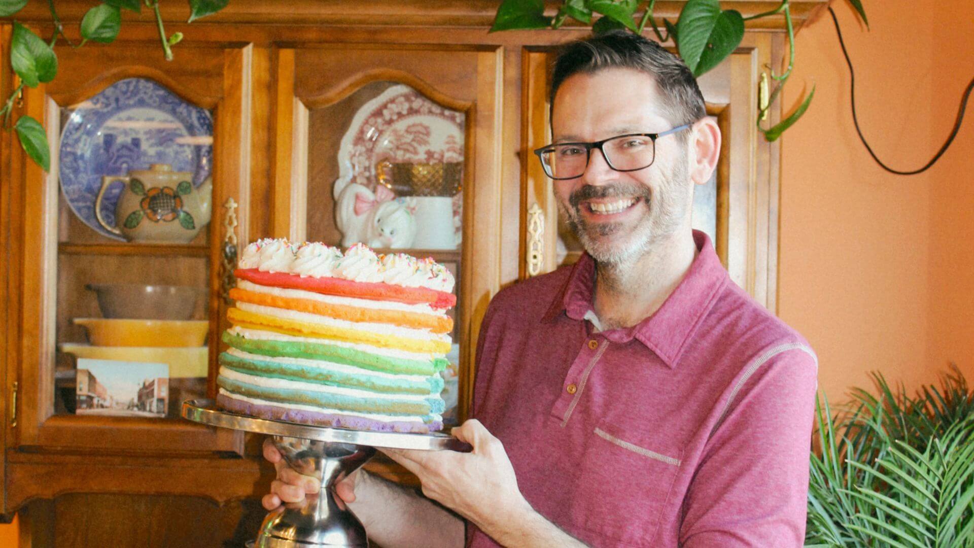 George + Kin’s team member holding a rainbow layer cake for Pride